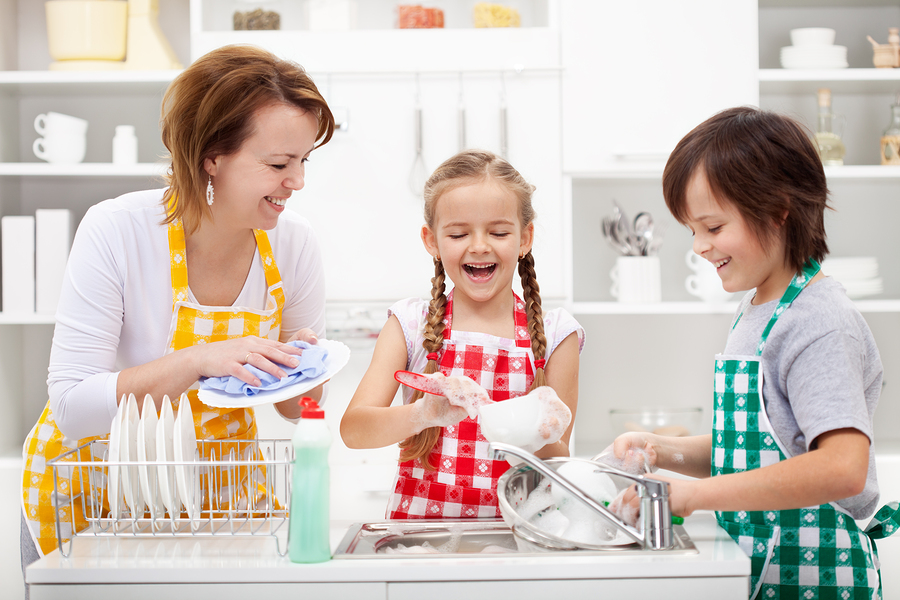 Kids and mother washing dishes - having fun together in the kitchen